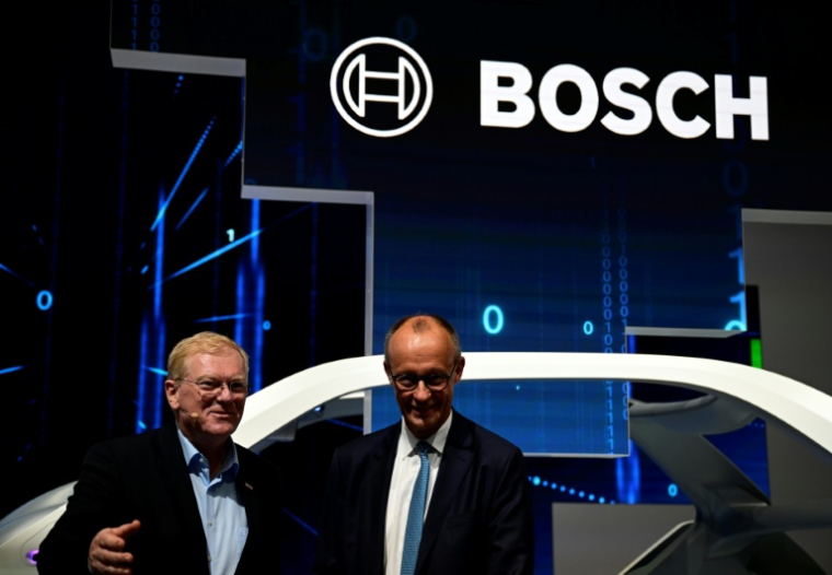 Le PDG de Bosch, Stefan Hartung (g) et le chancelier allemand lors de l'ouverture du Salon international de l'automobile IAA à Munich, le 9 septembre 2025 dans le sud de l'Allemagne ( AFP / Tobias SCHWARZ )