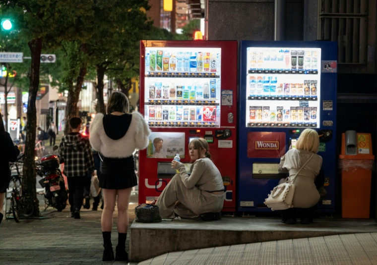 Des femmes se procurent des boissons auprès de distributeurs automatiques, le 13 avril 2026 à Tokyo ( AFP / Andrew CABALLERO-REYNOLDS )