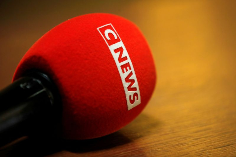 Le logo de CNEWS est visible sur un microphone alors que des journalistes travaillent au palais de justice de Paris
