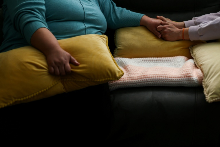 Ana (à gauche), une habitante mexicaine de Minneapolis, tend la main à une amie à son domicile le 31 janvier 2026, alors que la ville est le théâtre depuis plusieurs semaines de raids de la police de l'immigration (ICE) ( AFP / CHARLY TRIBALLEAU )