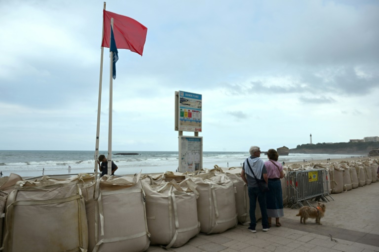 Un drapeau rouge interdisant la baignade sur la Grande plage de Biarritz, protégée par des sacs remplis de sable, le 26 août 2025, en prévision de la forte houle attendue ( AFP / Gaizka IROZ )