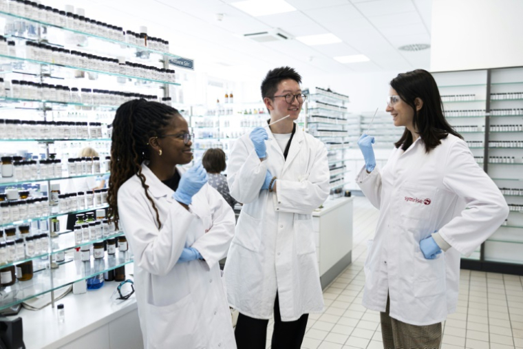(g-d) Les élèves parfumeurs Attiya Setai, Shangyun Lyu et Alicia de Benito Cassado sentent des bandelettes odorantes utilisées pour évaluer les parfums dans une salle de mélange du laboratoire du chimiste allemand Symrise, le 8 juillet 2025 à Holzminden, en Allemagne ( AFP / MICHAEL MATTHEY )
