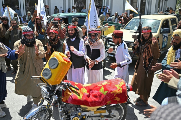 Des membres de forces de sécurité talibanes dansent autour d'une moto lors des célébrations des cinq ans du retour au pouvoir en Afghanistan de ce mouvement ultra-rigoriste, le 15 août 2026 à Kaboul  ( AFP / Wakil KOHSAR )