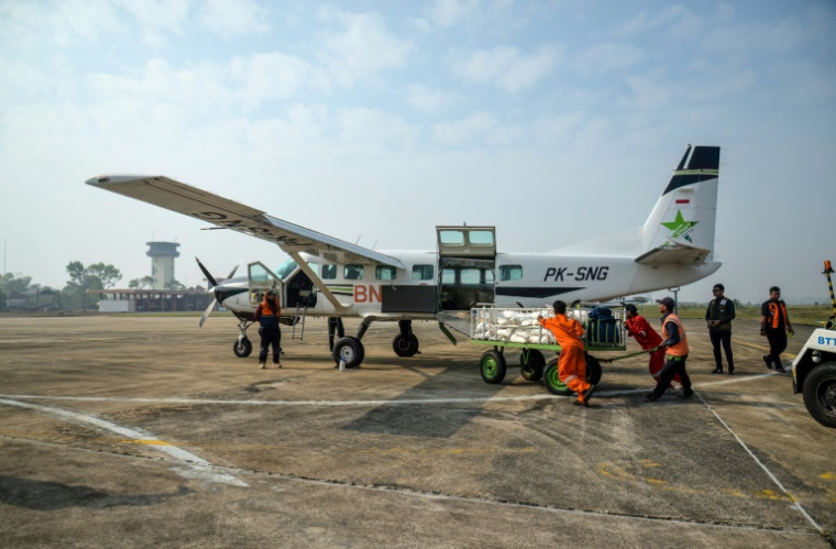 Des agents de l'Agence nationale de gestion des catastrophes chargent du chlorure de sodium dans un avion avant une opération d'ensemencement des nuages à Palangkaraya, dans le Kalimantan central, le 2 août 2026 en Indonésie ( AFP / REINA )