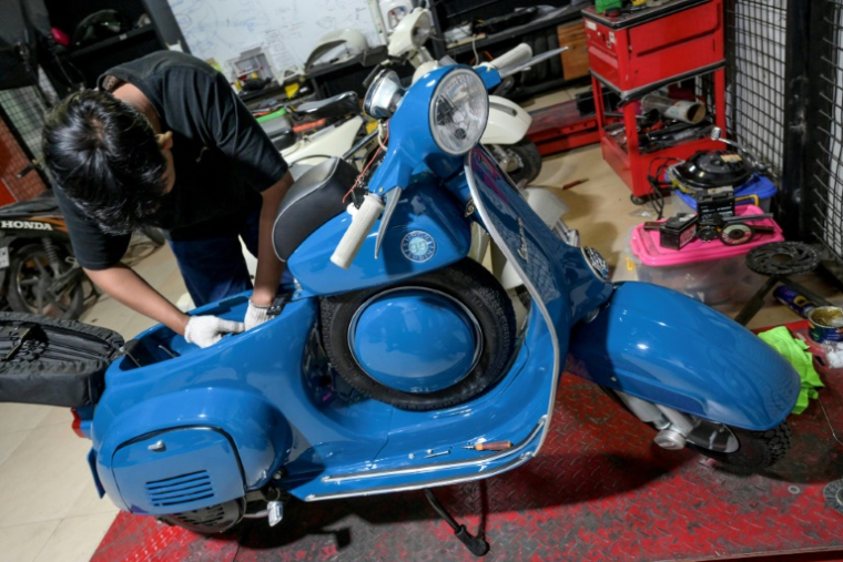 Un mécanicien prépare l'installation d'une batterie sur une Vespa, pour la convertir à l'électrique, le 3 mars 2025 à Jakarta ( AFP / BAY ISMOYO )