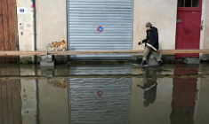 Un homme promène son chien dans une rue inondée d'Angers, le 20 février 2026  ( AFP / Damien MEYER )