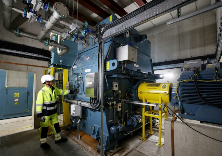 Guy Nicholson, responsable des solutions réseau neutres en carbone chez Statkraft, se tient près d'un volant d'inertie, le 7 août 2025 à Liverpool ( AFP / Darren Staples )