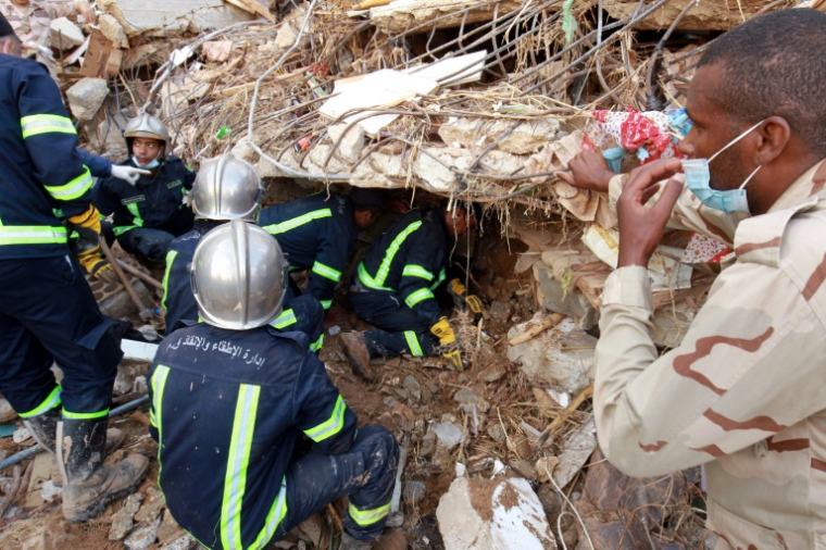 Pompiers et secouristes cherchant des survivants dans les décombres d'un immeuble effondré lors des inondations provoquées par la tempête qui a frappé la ville de Derna, dans l'est de la Libye, le 14 septembre 2023 ( AFP / Abdullah DOMA )