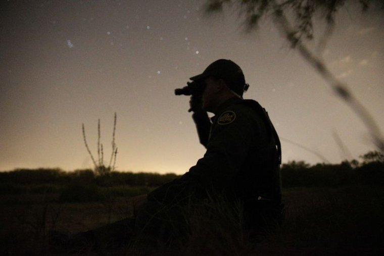 Un agent de la patrouille frontalière utilise des lunettes de vision nocturne pour rechercher les immigrants qui ont franchi illégalement la frontière entre le Mexique et les États-Unis, près de McAllen