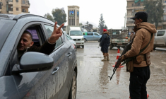 Un conducteur fait le V de la victoire en passant devant un membre des forces de syriennes, après la prise de contrôle par l'armée des quartiers kurdes d'Alep à l'issue de plusieurs jours de combats, le 11 janvier 2026 ( AFP / OMAR HAJ KADOUR )