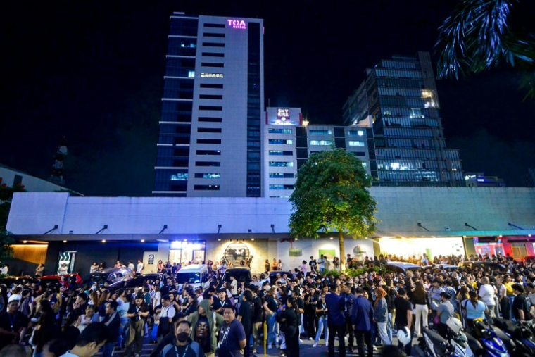 Les employés du centre d'appels surfent sur leurs téléphones portables alors qu'ils se rassemblent devant leur immeuble de bureaux après les secousses du tremblement de terre à Cebu, dans le centre des Philippines, le 30 septembre 2025 ( AFP / Alan TANGCAWAN )