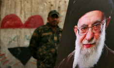 Un membre des Forces de mobilisation populaire irakiennes se tient derrière un portrait du guide suprême iranien défunt Ali Khamenei, à la veille de son cortège funère, au mausolée de l'imam Hussein à Karbala, en Irak, le 7 juillet 2026 ( AFP / AHMAD AL-RUBAYE )