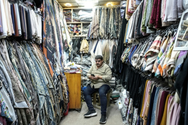 Un vendeur attend des clients dans sa boutique de vêtements de la vieille ville de Najaf, en Irak, le 22 avril 2026 ( AFP / Qassem al-KAABI )