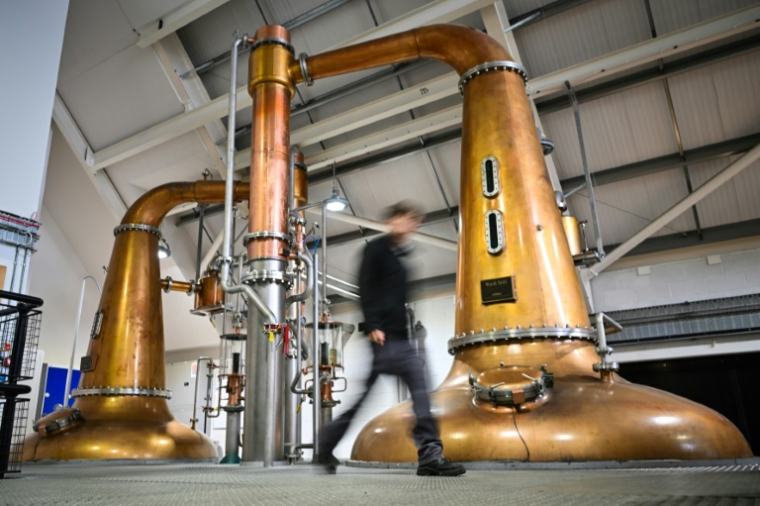 Donald MacRae passe devant un réservoir à la distillerie de l'île de Harris à Tarbert, le 28 avril 2025 en Ecosse ( AFP / Andy Buchanan )