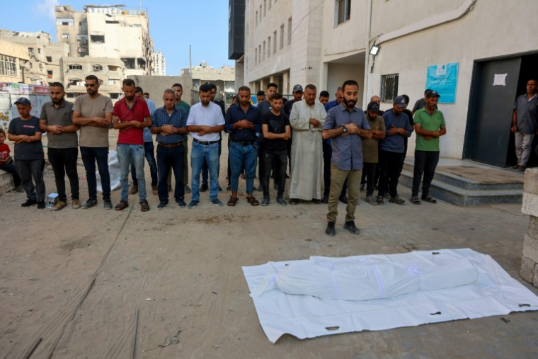 Des personnes se recueillent devant le corps d'une personne tuée la veille alors qu'elle tentait d'obtenir de l'aide à un point de distribution près du poste frontière de Zikim sous contrôle israélien, lors d'un service funèbre à l'hôpital Al-Chifa de Gaza, le 24 juin 2025 ( AFP / Omar AL-QATTAA )