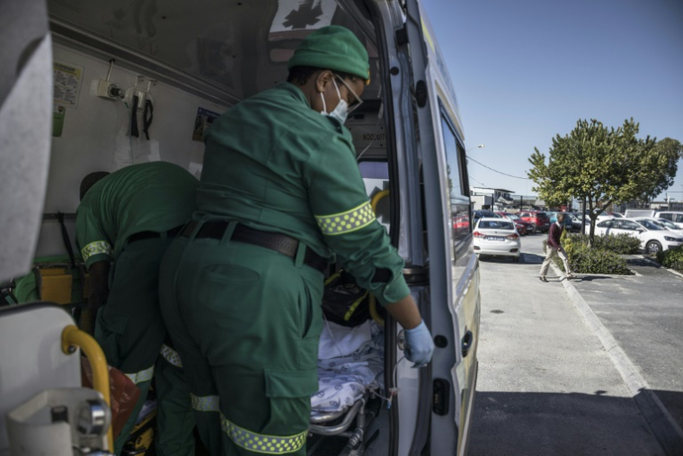 L'ambulancière Inathi Jacob (d) prépare une perfusion pour un jeune patient lors d'une intervention dans le township Philippi, près du Cap, le 17 avril 2025 en Afrique du Sud ( AFP / MARCO LONGARI )