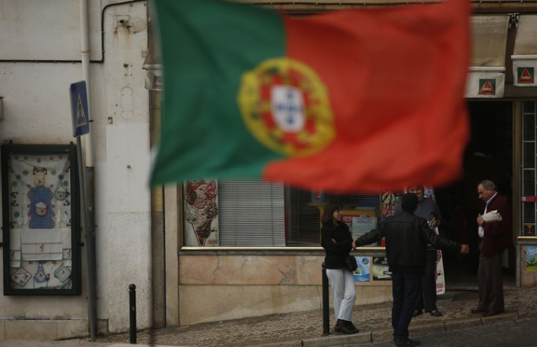 Des personnes discutent près d'un drapeau portugais dans le centre de Lisbonne