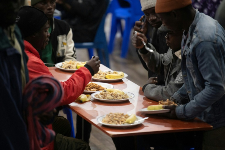 Des étrangers, principalement originaires du Malawi, reçoivent un repas après avoir trouvé refuge dans une salle communautaire à Kleinmond, à environ 100 km du Cap (Afrique du Sud), le 2 juin 2026, après avoir été menacés par des groupes anti-migrants ( AFP / RODGER BOSCH )