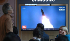 Des personnes sont assises devant un écran de télévision diffusant un journal télévisé avec des images d'archives d'un test de missile nord-coréen, dans une gare de Séoul, le 22 octobre 2025 ( AFP / Jung Yeon-je )