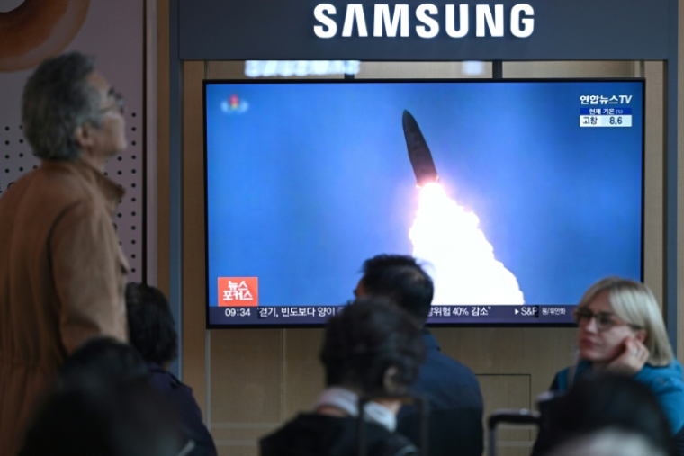 Des personnes sont assises devant un écran de télévision diffusant un journal télévisé avec des images d'archives d'un test de missile nord-coréen, dans une gare de Séoul, le 22 octobre 2025 ( AFP / Jung Yeon-je )