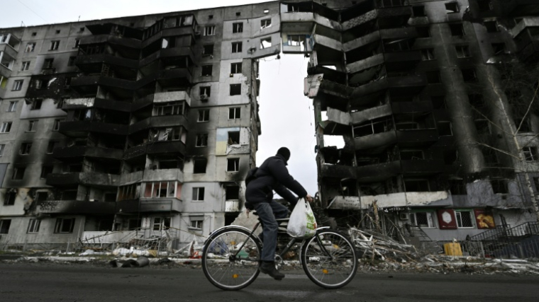 Un cycliste passe devant un bâtiment endommagé à Borodianka, au nord de Kiev, le 6 avril 2022 ( AFP / Genya SAVILOV )