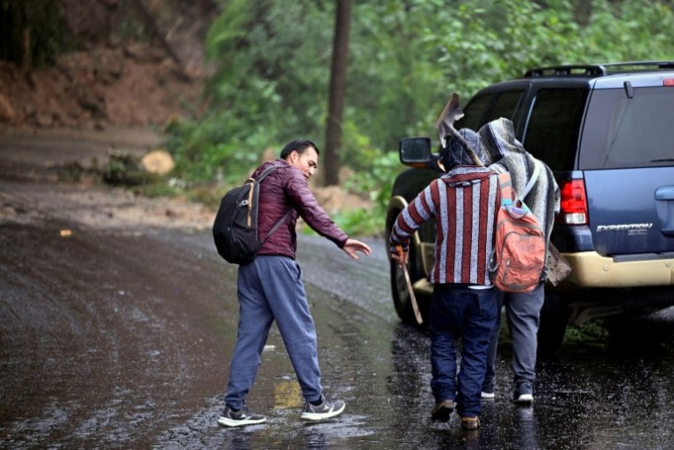 Des personnes marchent le long de la route Tulancingo-Tenango bloquée par de la boue et des chutes de pierres, en raison de pluies torrentielles, le 11 octobre 2025 au Mexique ( AFP / Alfredo ESTRELLA )