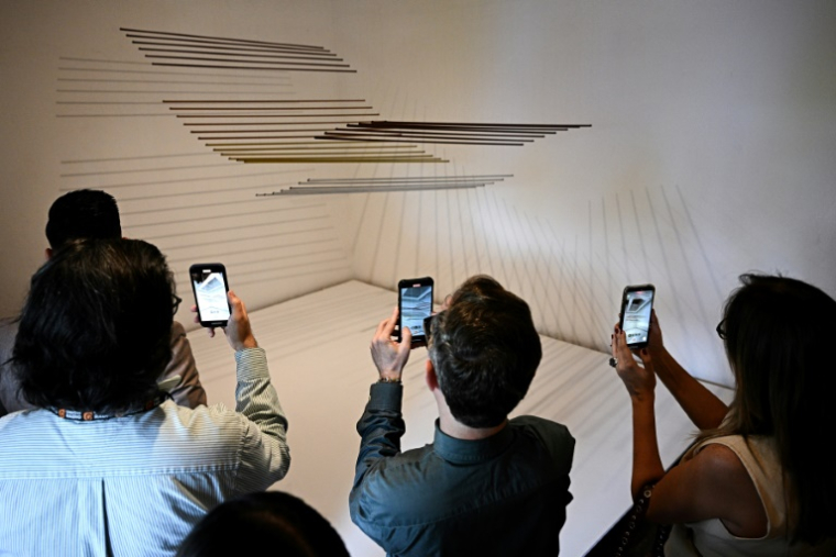 Des visiteurs photographient une oeuvre de l'exposition "Continuum" de l'artiste vénézuélien Elias Crespin à la galerie d'art Hacienda La Trinidad à Caracas, le 28 mai 2025 au Venezuela ( AFP / Federico PARRA )
