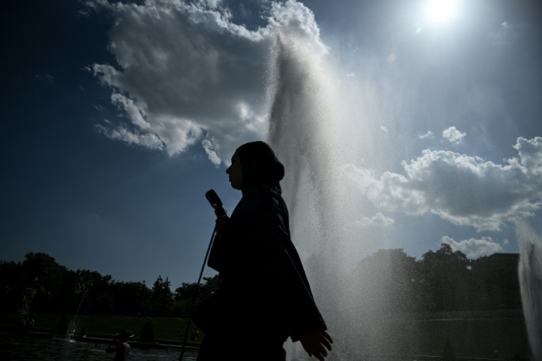 Une passante tient un ventilateur portatif devant la fontaine du Trocadéro, le 22 juin 2026 à Paris, lors d'un épisode de canicule en France ( AFP / JULIEN DE ROSA )