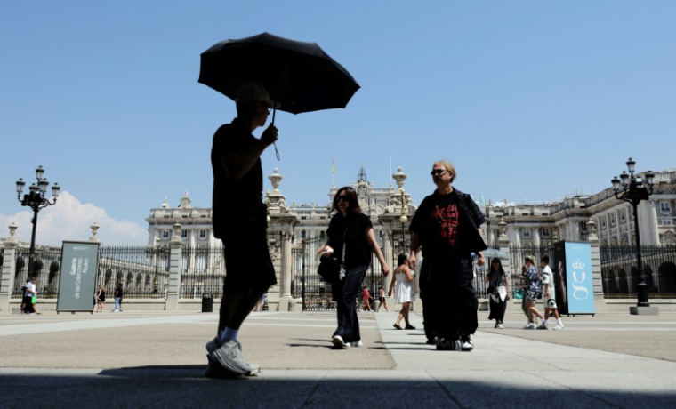 Un passant se protège du soleil à Madrid pendant une vague de chaleur en Espagne, le 2 juillet 2025 ( AFP / Thomas COEX )