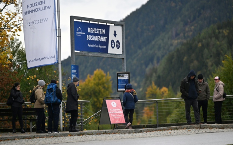 Des personnes se tiennent au départ des bus pour la navette montant à la maison d’hôtes de montagne Kehlsteinhaus, connue sous le nom de « Nid d’aigle », ancien refuge de montagne d’Adolf Hitler, le 24 octobre 2026, tandis qu’un panneau indique « Kehlsteinhaus fermé » après qu’un important incendie s’est déclaré sur le site situé à une altitude de 1 834 mètres (6 000 pieds) dans les montagnes dominant Berchtesgaden, dans le Land de Bavière, au sud de l’Allemagne. ( AFP / KERSTIN JOENSSON )