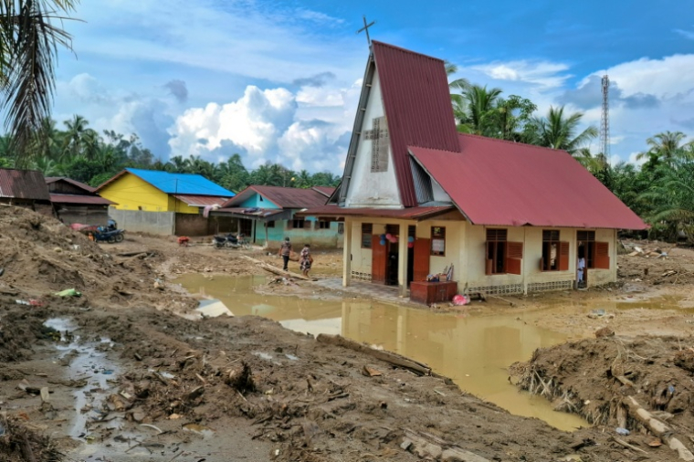 Des villageois se rendent à l'église protestante d'Angkola pour la messe de Noël, dans le village d'Aek Ngadol, le 25 décembre 2025, dans la province de Sumatra touchée par des inondations et glissements de terrain meurtriers, en Indonésie ( AFP / AMROE )