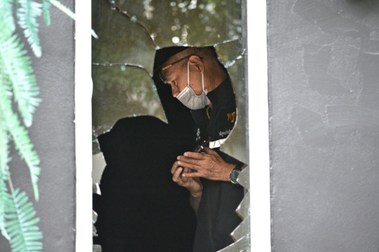 Un membre de la police scientifique inspecte l'intérieur du bar-restaurant Rong Beer Na Lat Phrao  à Bangkok après un incendie meurtrier, le 13 juillet 2026 ( AFP / Lillian SUWANRUMPHA )