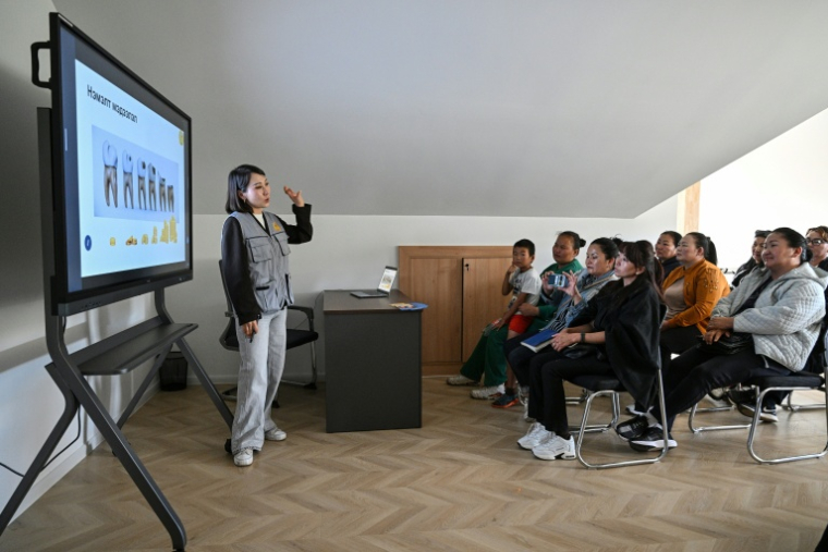Namuunaa, dentiste pédiatrique mongole et cheffe de projet de la  Misheel Kids Foundation, enseigne l'hygiène bucco-dentaire à des personnes à Oulan-Bator, le 28 août 2026 ( AFP / Hector RETAMAL )