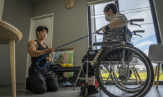 Hokuto Tatsumi (g), auxiliaire de vie et culturiste, aide une patiente (d) à s'entraîner dans un foyer pour personnes handicapées géré par Visionary à Ichinomiya, au Japon, le 29 septembre 2025 ( AFP / Yuichi YAMAZAKI )