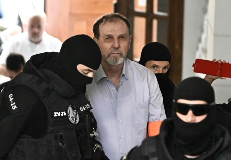 Des policiers escortent Juraj Cintula (c) jusqu'à la salle d'audience de Banska Bystrica, pour le début de son procès où il est accusé d'avoir tiré sur le Premier ministre slovaque Robert Fico en mai 2024, le 8 juillet 2025 en Slovaquie ( AFP / Joe Klamar )