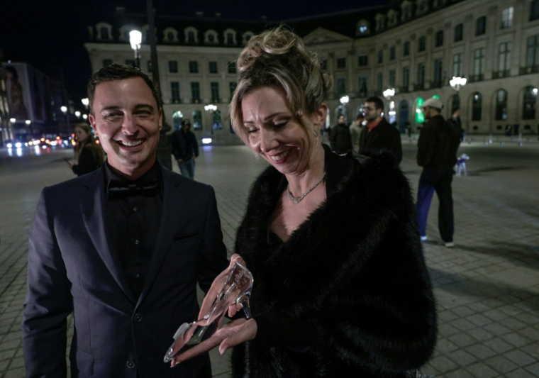 Un couple néerlandais tient une chaussure de verre en référence à la chaussure de Cendrillon lors de leur demande en mariage à Paris, le 7 février 2026 ( AFP / STEPHANE DE SAKUTIN )