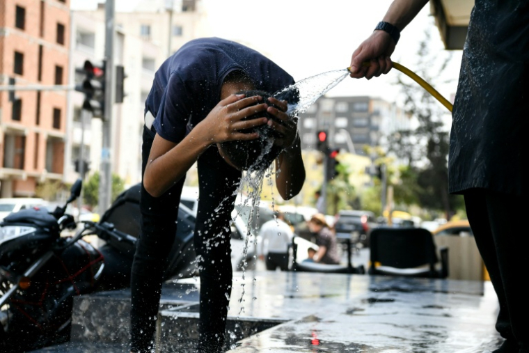 Un homme passe sa tête sous l'eau à Sirnak, en Turquie, lors d'une vague de chaleur extrême, le 30 juillet 2025 ( AFP / Ilyas AKENGIN )