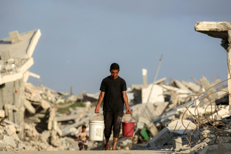 Un homme porte des seaux d'eau le 2 septembre 2025 dans la ville de Gaza ( AFP / Eyad BABA )