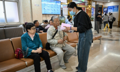 Meng Jia (d), une accompagnatrice de patient, prend en charge Gao Yingmin (g) et Tian Yigui (c) pour les guider dans un hôpital à Pékin, le 22 mai 2025 ( AFP / Jade GAO )