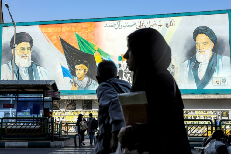 Une femme marche près d'un panneau montrant les ayatollahs Rouhollah Khomeini et Ali Khamenei, le 21 février 2026 à Téhéran ( AFP / - )