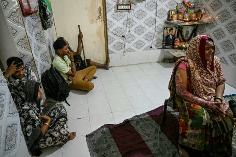 Sita Patni (d), qui a été brûlée et a perdu son fils Akash Patni dans le crash du vol 171 d'Air India,  entourée de ses proches lors d'un entretien avec l'AFP à son domicile à Ahmedabad, le 8 novembre 2025 en Inde  ( AFP / Indranil MUKHERJEE )