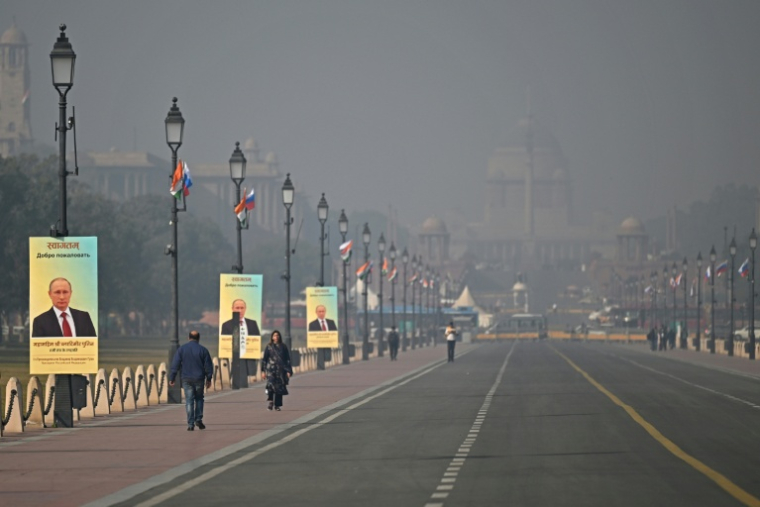 Des passants devant des portraits du président russe Vladimir Poutine à New Delhi le 4 décembre 2025 ( AFP / Sajjad HUSSAIN )