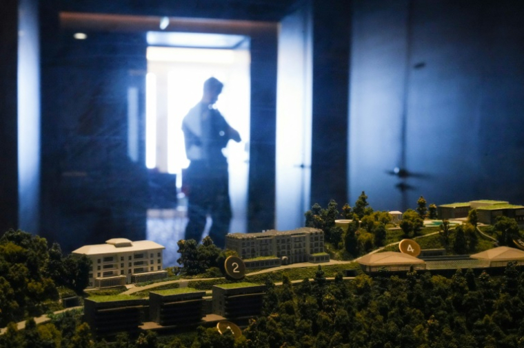 Un policier passe devant une maquette du complexe hôtelier de luxe du Bürgenstock, surplombant le lac des Quatre-Cantons, le 21 juin 2026 près de Lucerne, en Suisse ( POOL / Nathan Howard )
