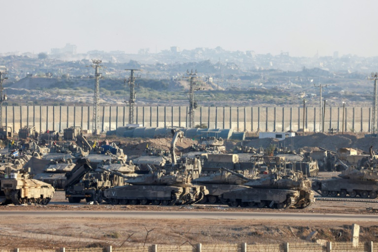 Une photo prise depuis la frontière israélienne avec la bande de Gaza montre des véhicules blindés militaires israéliens stationnés face aux bâtiments détruits dans le territoire palestinien, le 16 septembre 2025 ( AFP / Menahem Kahana )