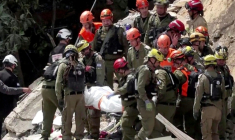 Image tirée d'une vidéo d'AFPTV montrant des équipes de secours  sortant les corps de victimes des décombres d'un immeuble résidentiel détruit par une attaque de missile iranienne dans la ville de Haïfa, dans le nord d'Israël, le 6 avril 2026 ( AFPTV / Jorge NOVOMINSKY )