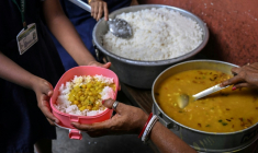 Une élève reçoit son repas de midi dans une école primaire publique de Calcutta, le 9 juillet 2026 en Inde ( AFP / Dibyangshu SARKAR )