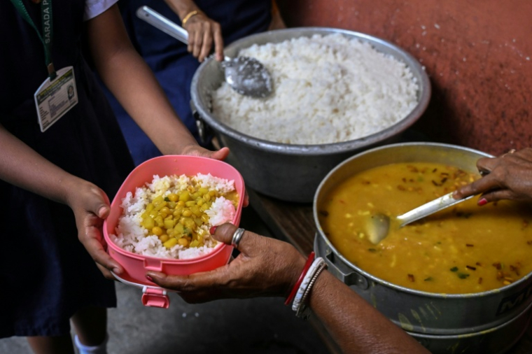 Une élève reçoit son repas de midi dans une école primaire publique de Calcutta, le 9 juillet 2026 en Inde ( AFP / Dibyangshu SARKAR )