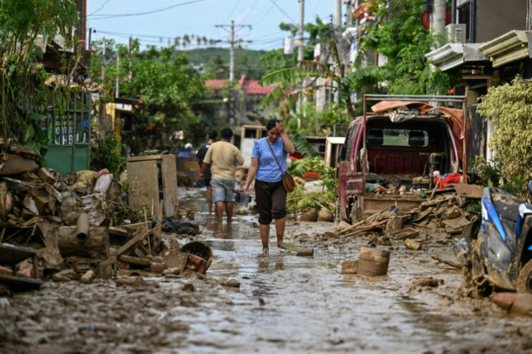 Une femme marche le long d'une rue couverte de boue après le passage du typhon Kalmaegi à Liloan, dans la province de Cebu aux Philippines, le 6 novembre 2025 ( AFP / Jam STA ROSA )