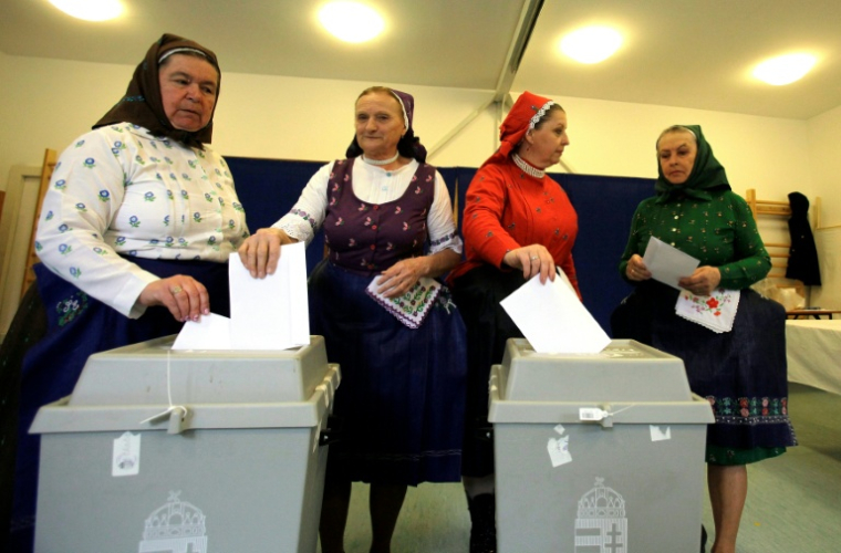 Des femmes en tenue traditionnelle votent dans une école maternelle à Veresegyhaz, près de Budapest, le 12 avril 2026 ( AFP / Peter Kohalmi )