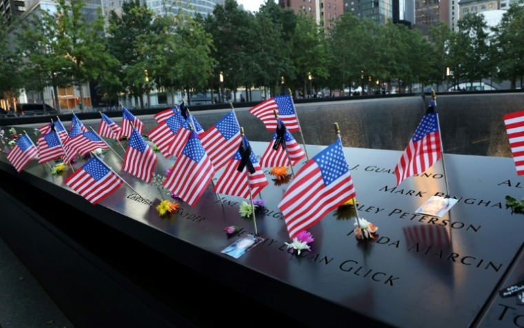 Des drapeaux américains placés sur le mur du bassin de la tour sud du Mémorial national du 11 septembre, au complexe du World Trade Center, le 11 septembre 2025, avant le début des cérémonies marquant le 24e anniversaire des attentats terroristes du 11 septembre 2001, à New York ( AFP / TIMOTHY A. CLARY )
